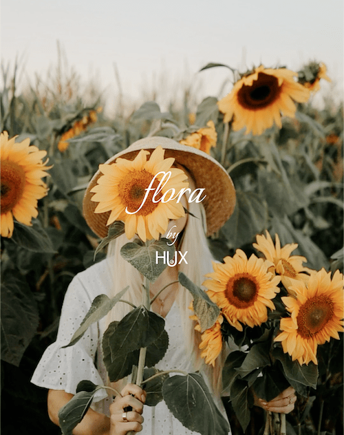 Poster for flora's branding: a girl in a sunflowers field, holding a bouquet of sunflowers, one of them is hiding her face.